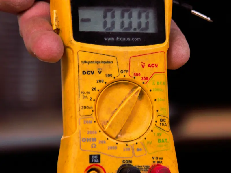 Engineer testing battery cell voltage with a multimeter, Barns Industrial Battery Services